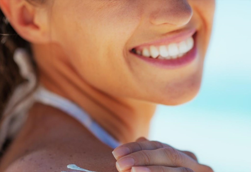 closeuponhappyyoungwomanapplyingsunblockcreme